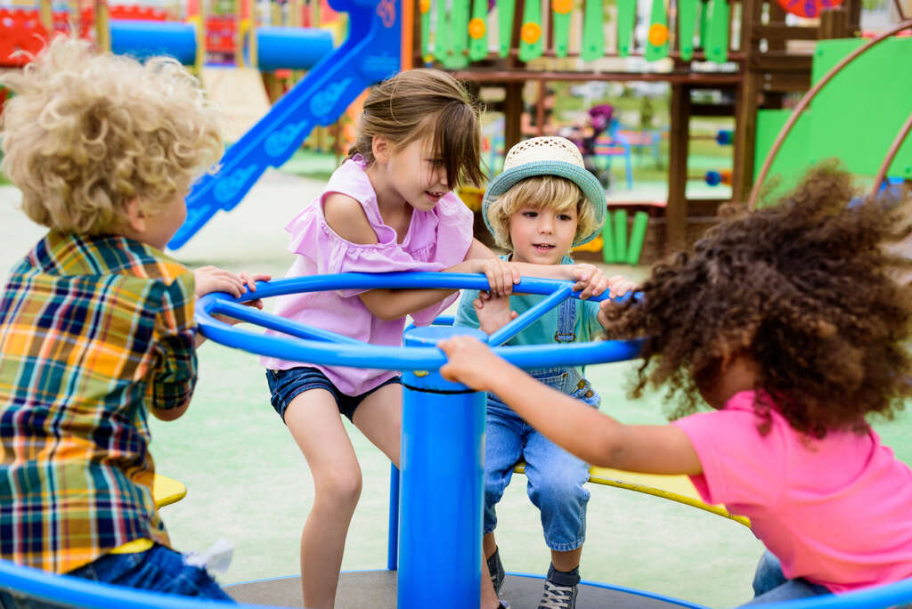 little kids riding on carousel at playground